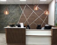 Profi sportolók komplex orvosi ellátására szakosodott budapesti magánkórház impozáns recepciós pultja, melyet szépen kiemel a falon megjelenő Burning Forest struktúrájú Slate Design ultravékony kőfurnér